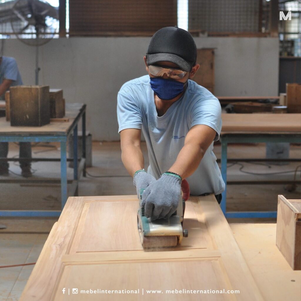 Worker sanding wooden panel at Mebel International furniture manufacturer workshop