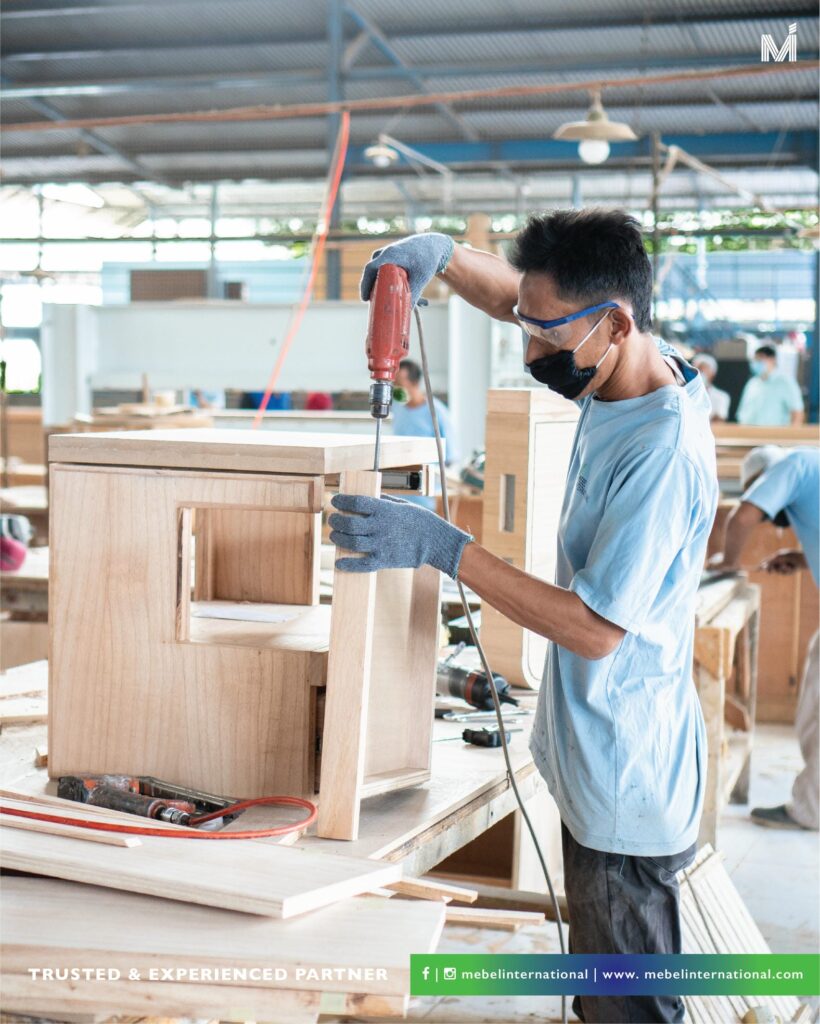 Mebel International furniture manufacturer craftsman assembling wooden cabinet using power drill